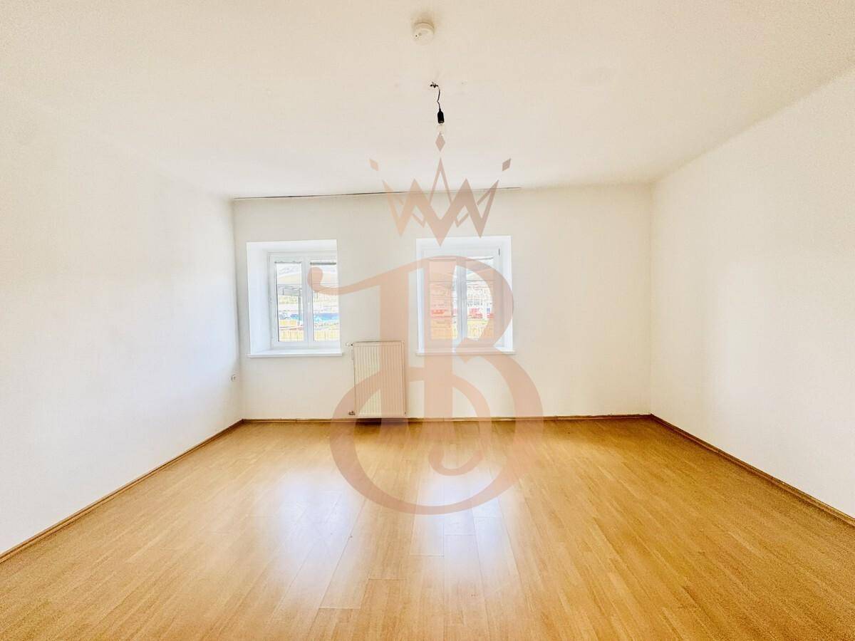 Helles Schlafzimmer mit Parkettboden und zwei Fenstern, die viel Licht hereinlassen.