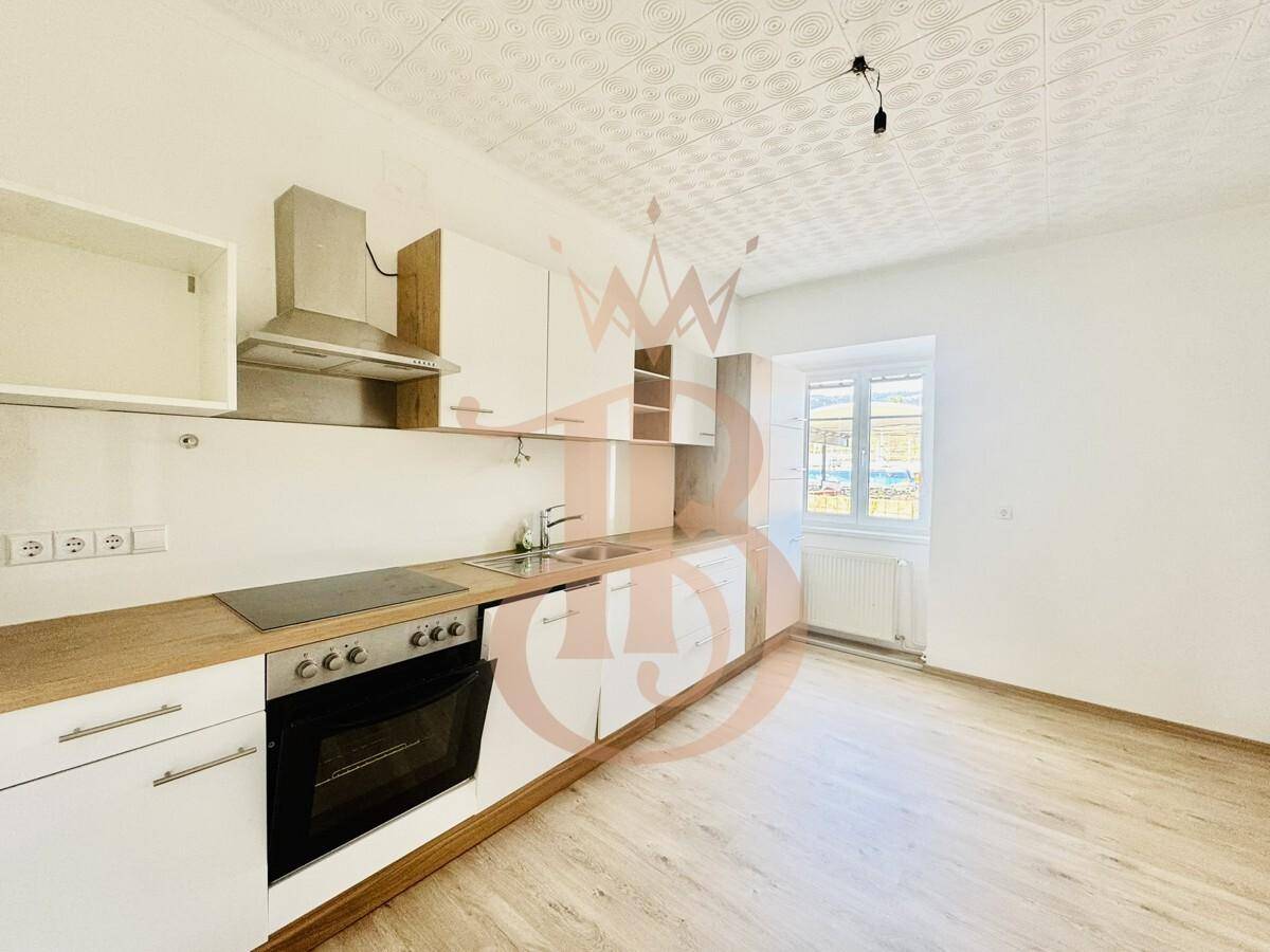 Helle Küche mit modernen Schränken, Holz-Arbeitsplatte und Fenster für Tageslicht.