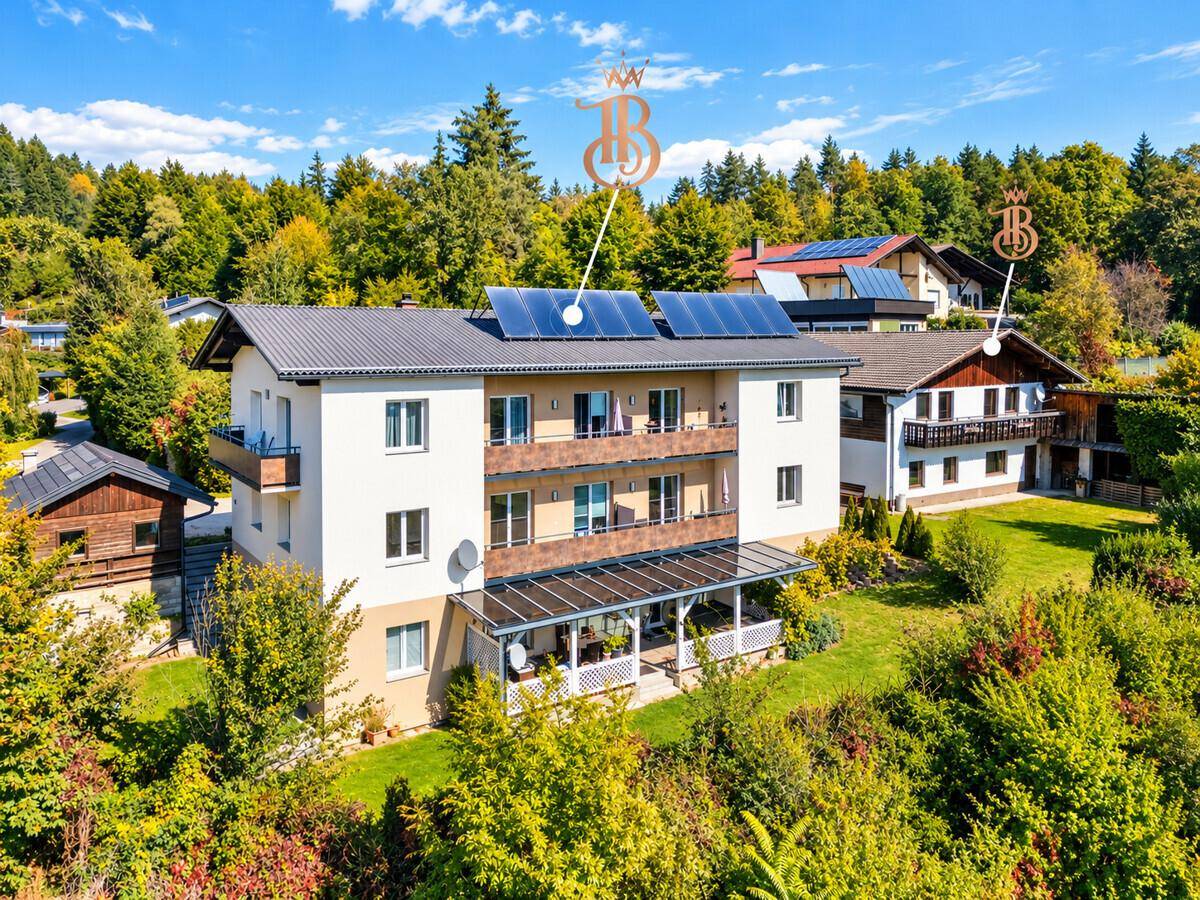 Drohnenansicht des Hauptgebäudes mit Balkonen und Solaranlage, umgeben von viel Grün.