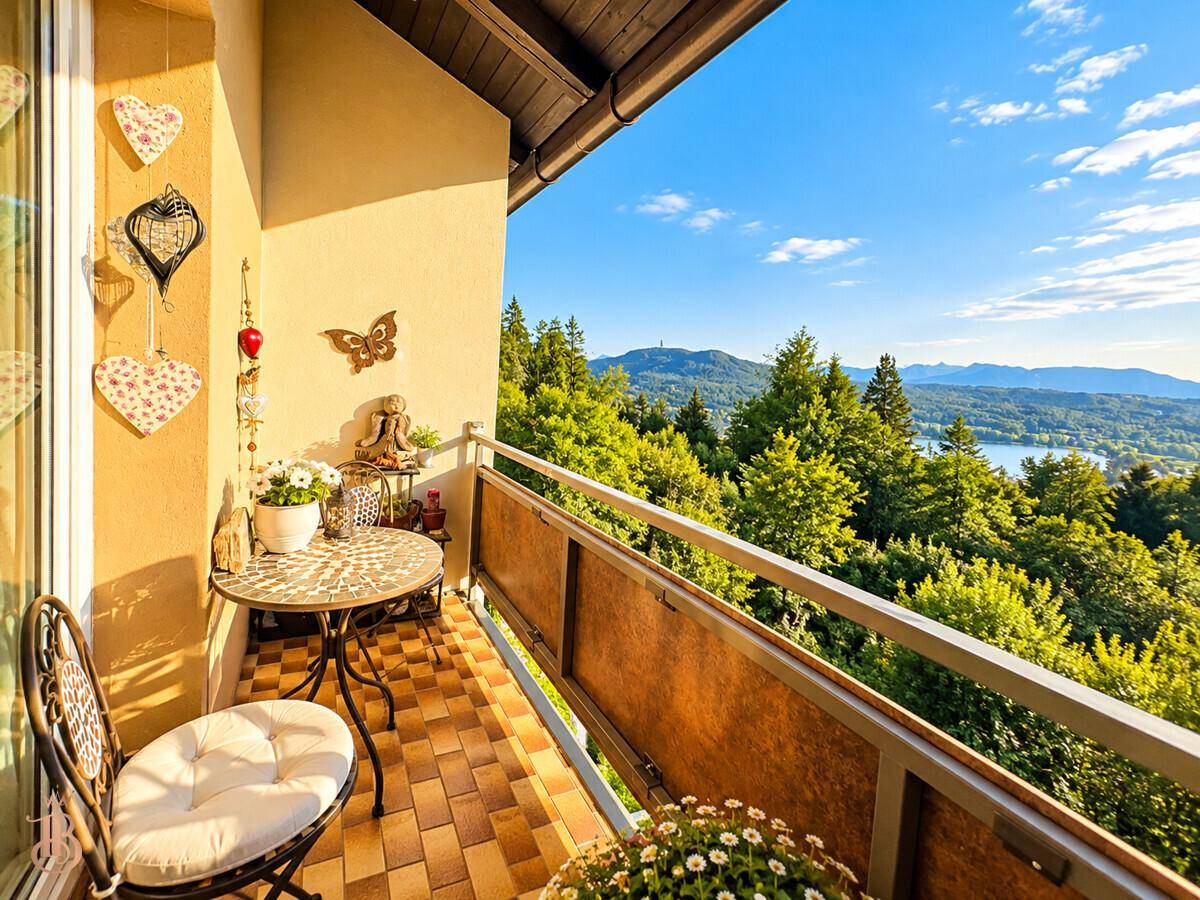 Gemütlicher Balkon mit Sitzgelegenheiten und weitem Blick auf die bewaldete Landschaft und den See.
