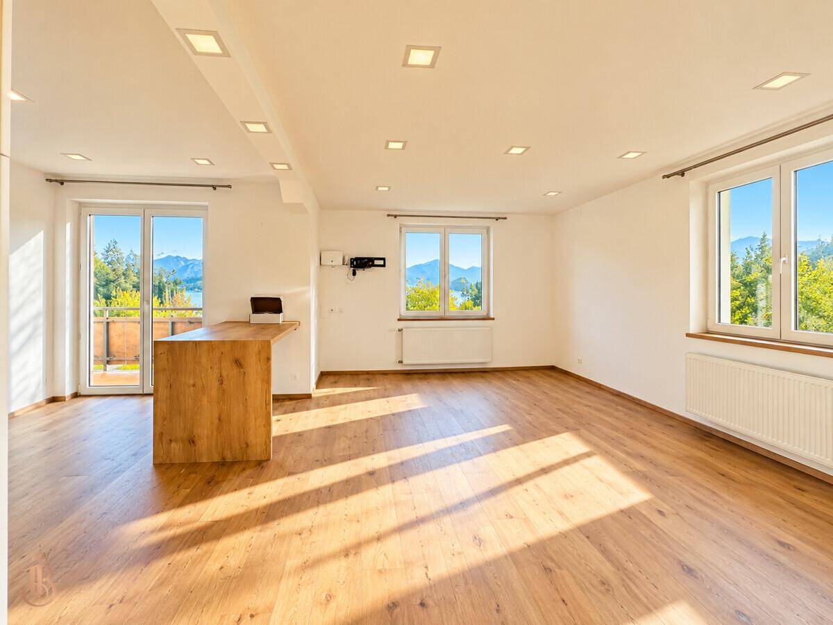 Geräumiger, heller Wohnbereich mit Holzboden, großen Fenstern und viel natürlichem Licht.