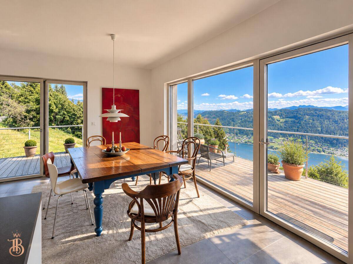 Heller Essbereich mit Holztisch und direktem Zugang zur Terrasse mit Seeblick.