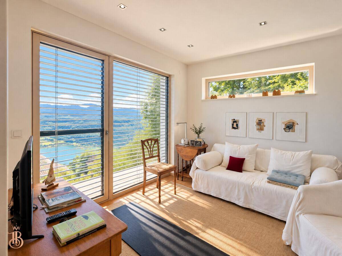 Gemütlicher Wohnraum mit Sofa, großen Fenstern und weitem Blick auf die malerische Seenlandschaft.