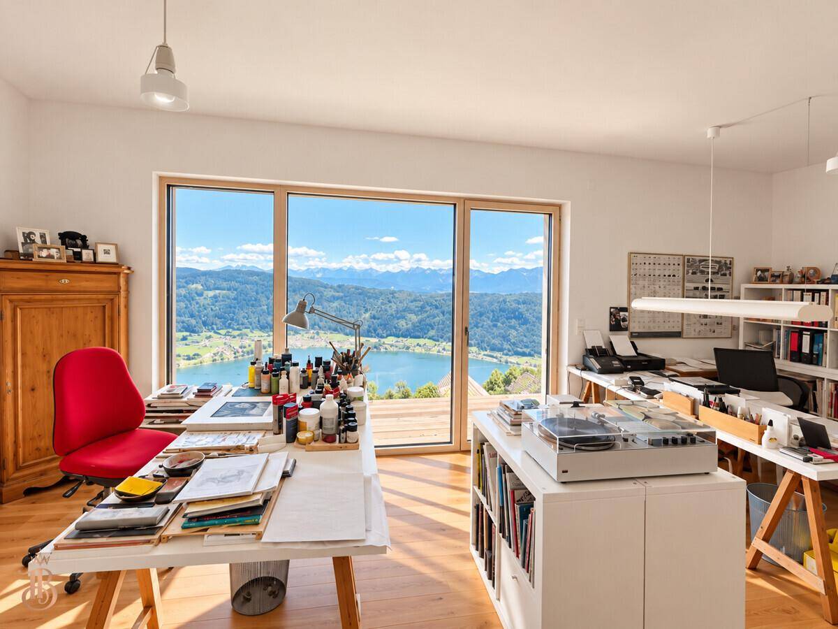 Helles Arbeitszimmer mit großem Fenster und inspirierendem Blick auf den See und die umliegende Natur.