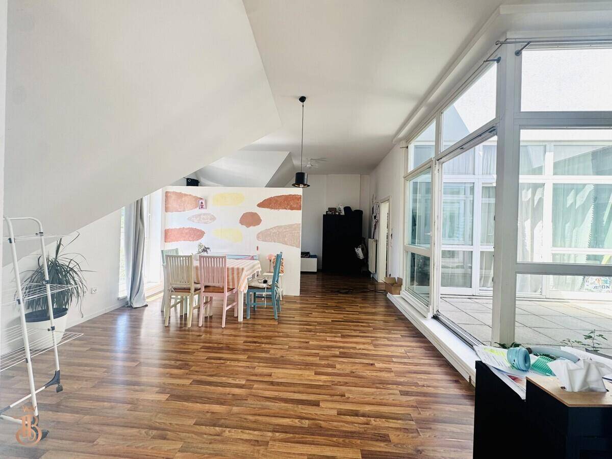 Lichtdurchfluteter offener Wohn-Essbereich mit Holzboden und großen Fensterfronten.