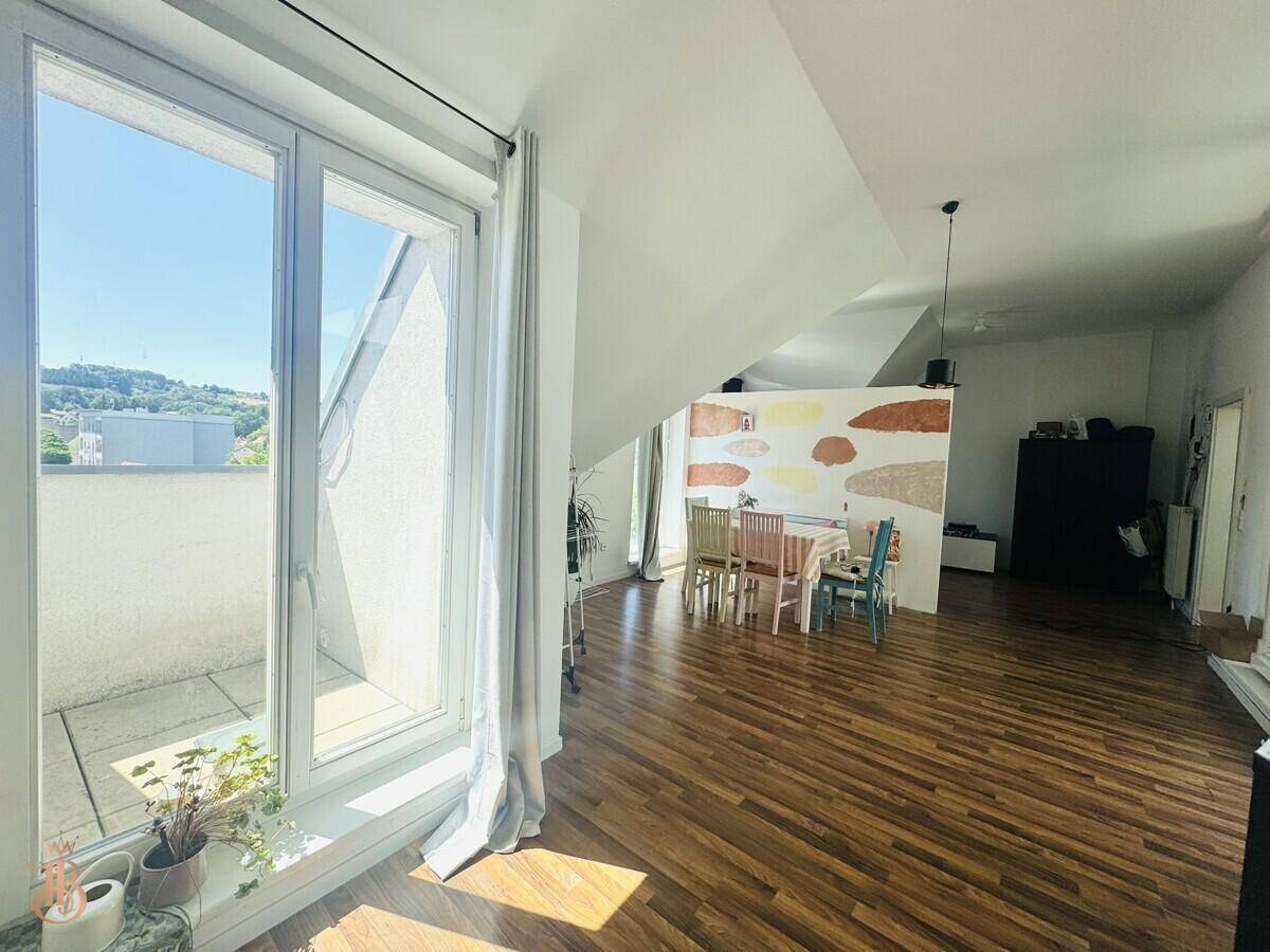 Geräumiger Wohn-Essbereich mit Holzboden, Dachschräge und Zugang zur Terrasse.