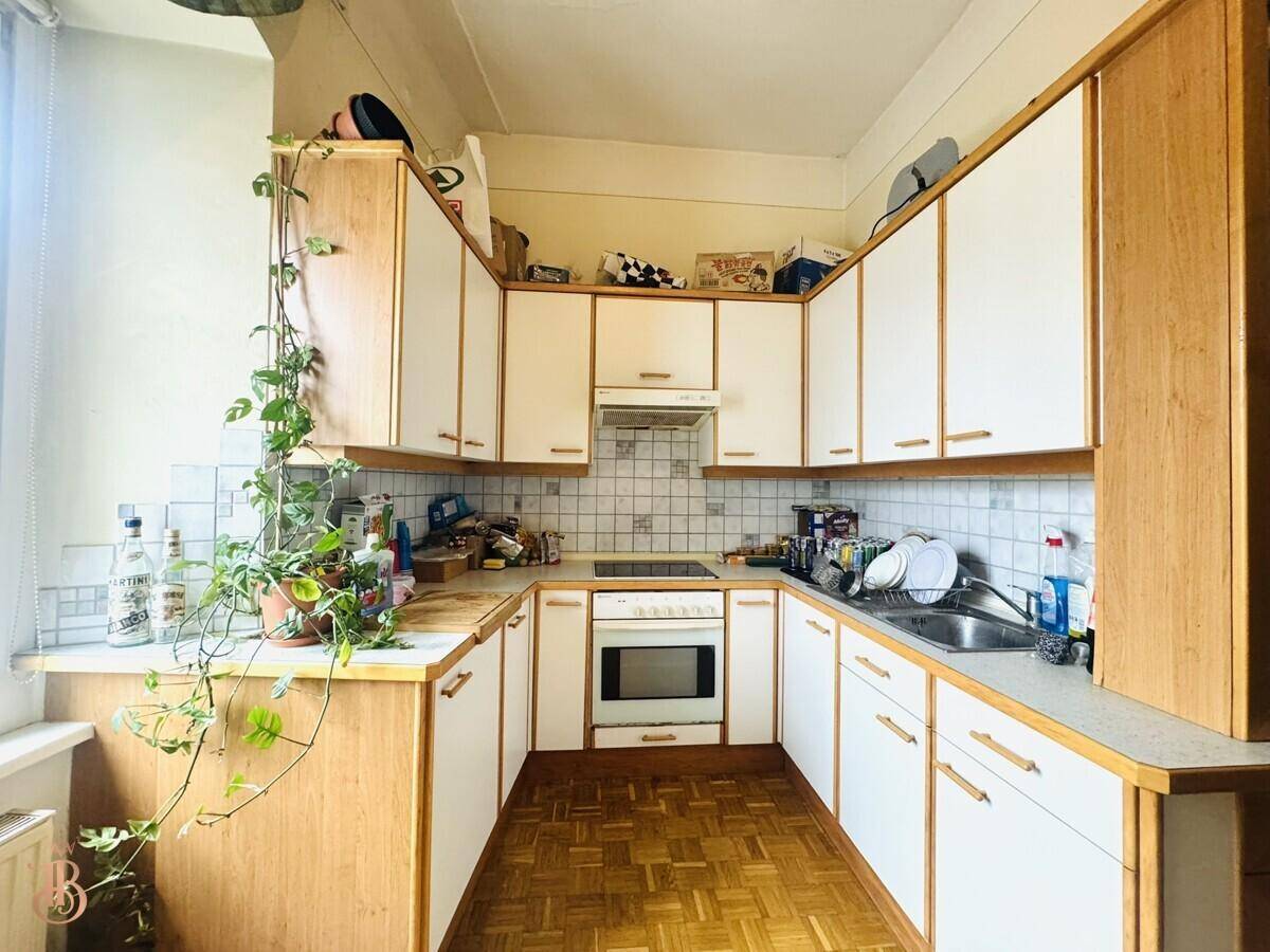 Küche mit U-förmiger Anordnung, weißen Schränken, Holzfronten und Fliesenboden, gut ausgestattet.