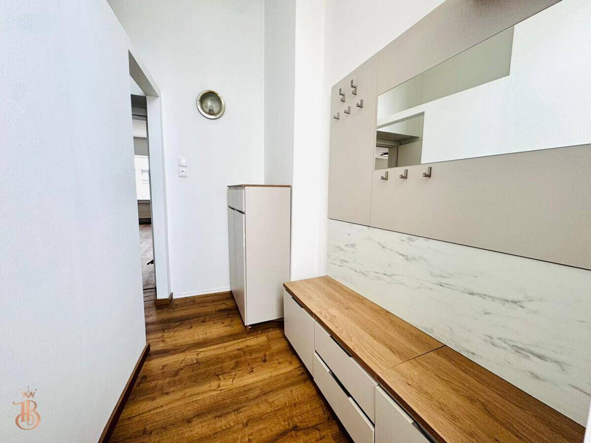 Moderner Flur mit integrierter Garderobe, Spiegel und Ablageflächen in hellem Design.