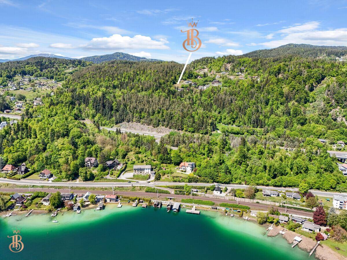 Weitläufige Luftaufnahme der Seenlandschaft mit bewaldeten Hügeln und Siedlungen am Ufer.