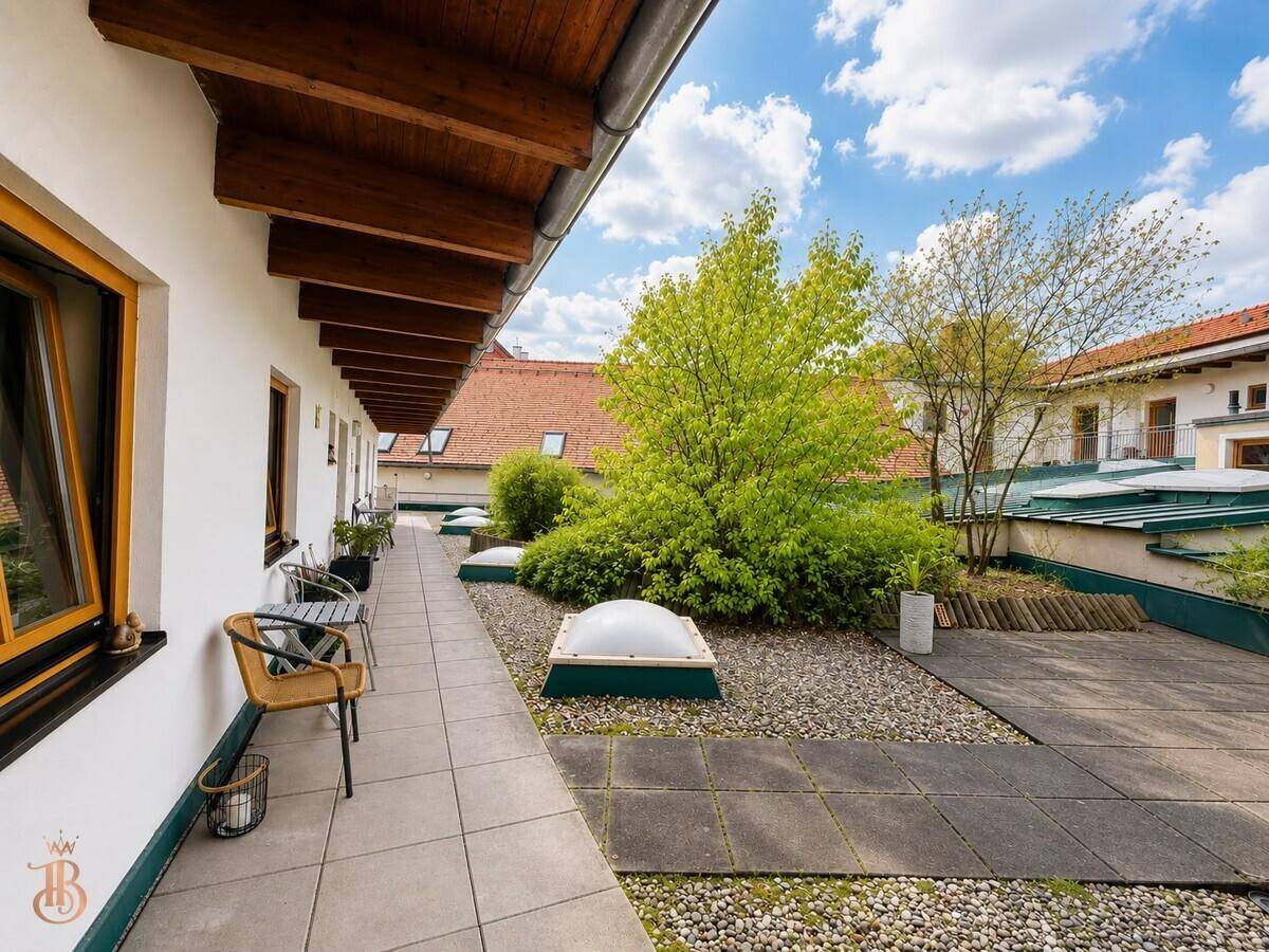 Überdachte Dachterrasse mit Holzbalken, Sitzgelegenheiten und Blick auf die Umgebung.