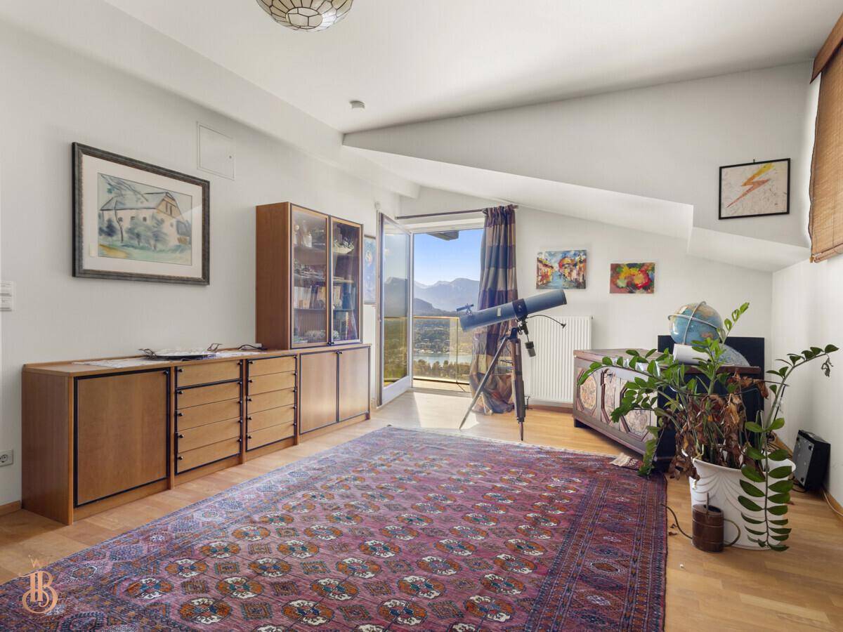 Geräumiges Arbeitszimmer mit Holzboden, Teppich und Zugang zu einem Balkon mit Aussicht.