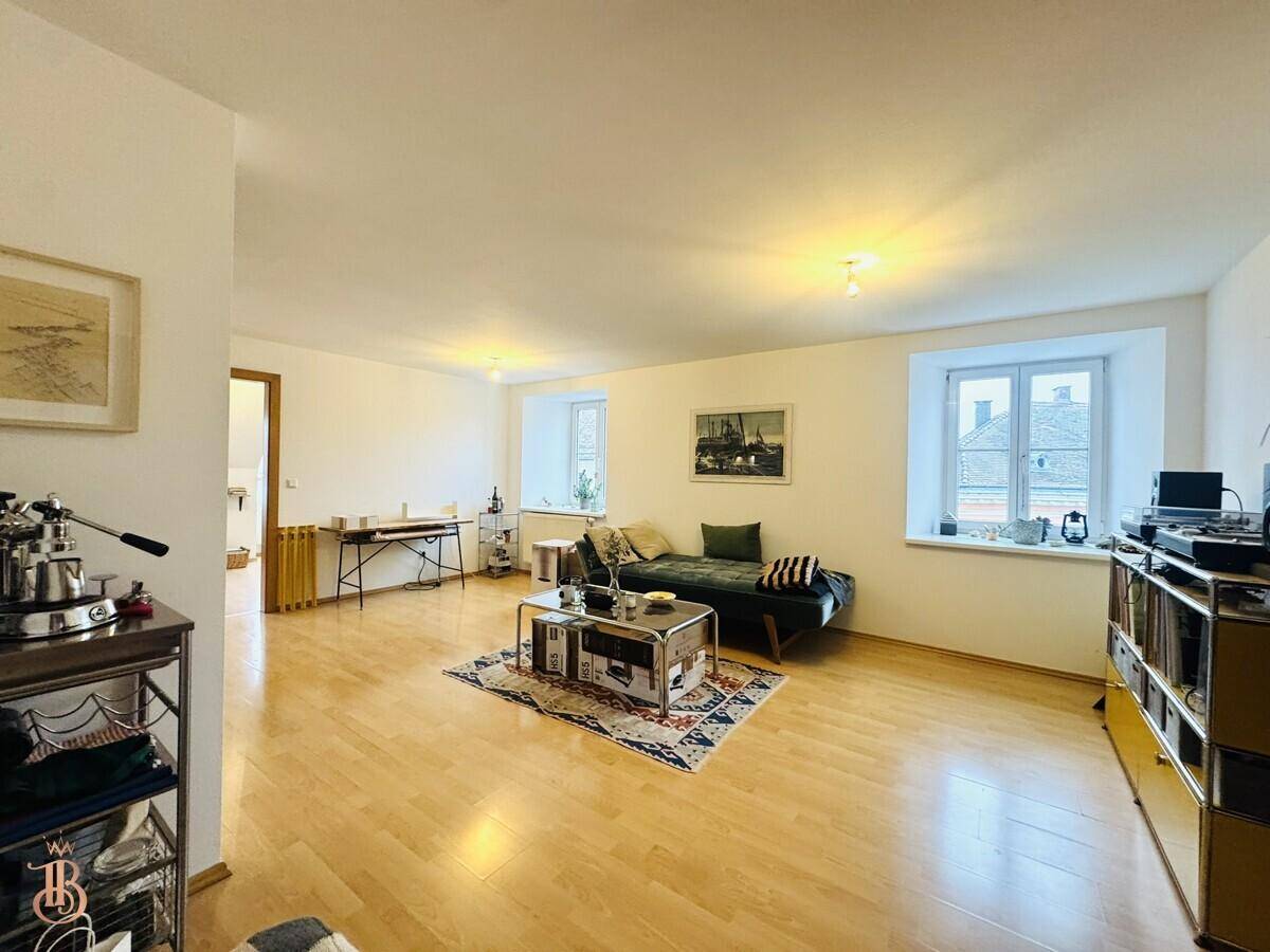 Helles Wohnzimmer mit Holzboden, gemütlichem Sofa und Blick auf die Stadt.