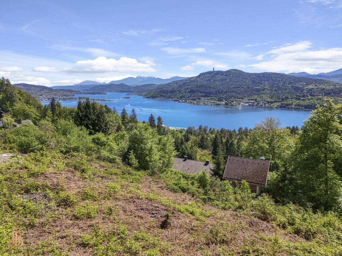 Malerischer Ausblick auf den See und die bewaldeten Hügel mit traditionellen Häusern in der Ferne.