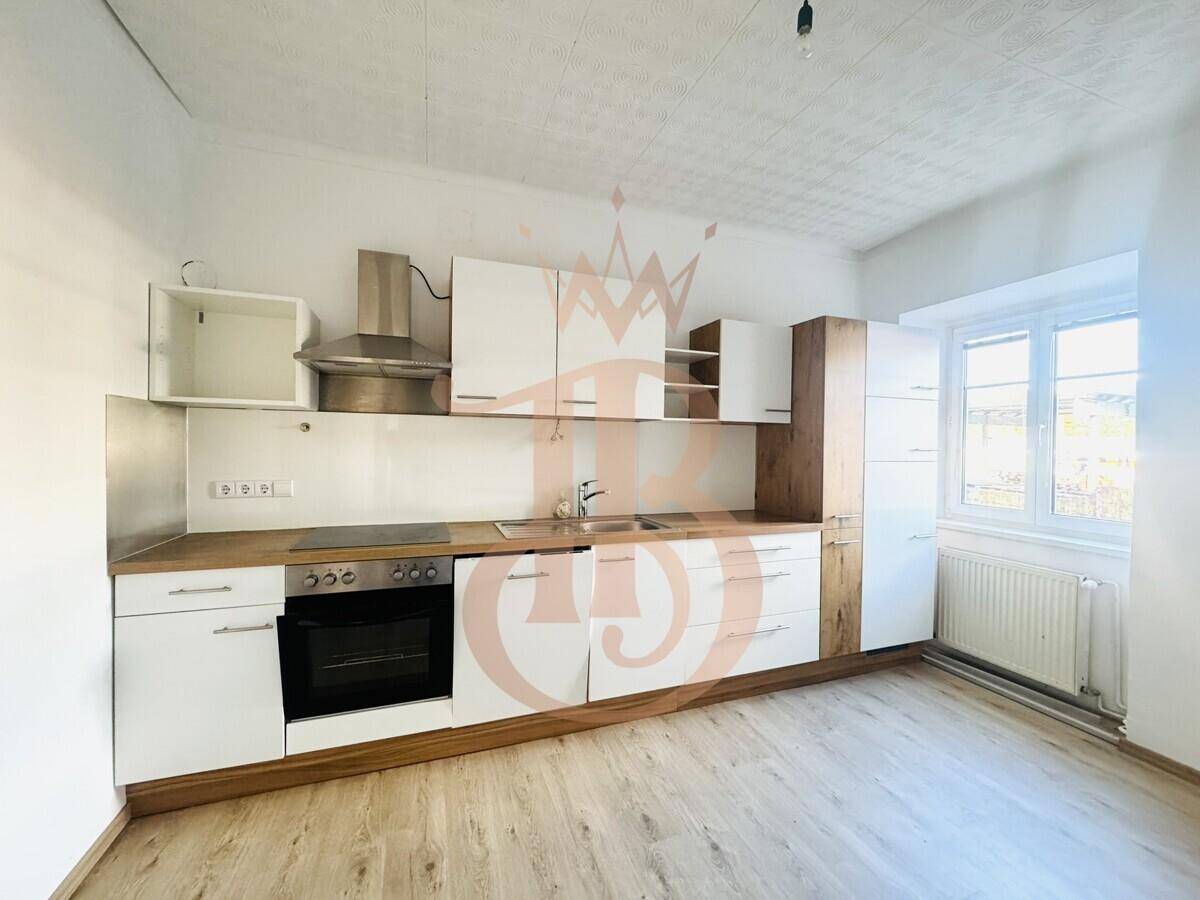Moderne Küche mit weißen und holzfarbenen Schränken, Induktionskochfeld und Dunstabzugshaube.
