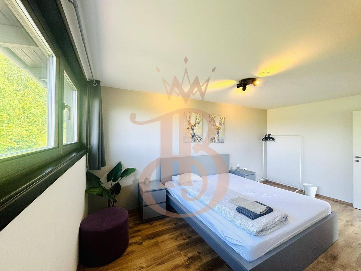 Gemütliches Schlafzimmer mit Holzboden, Doppelbett und Blick ins Grüne durch das Fenster.