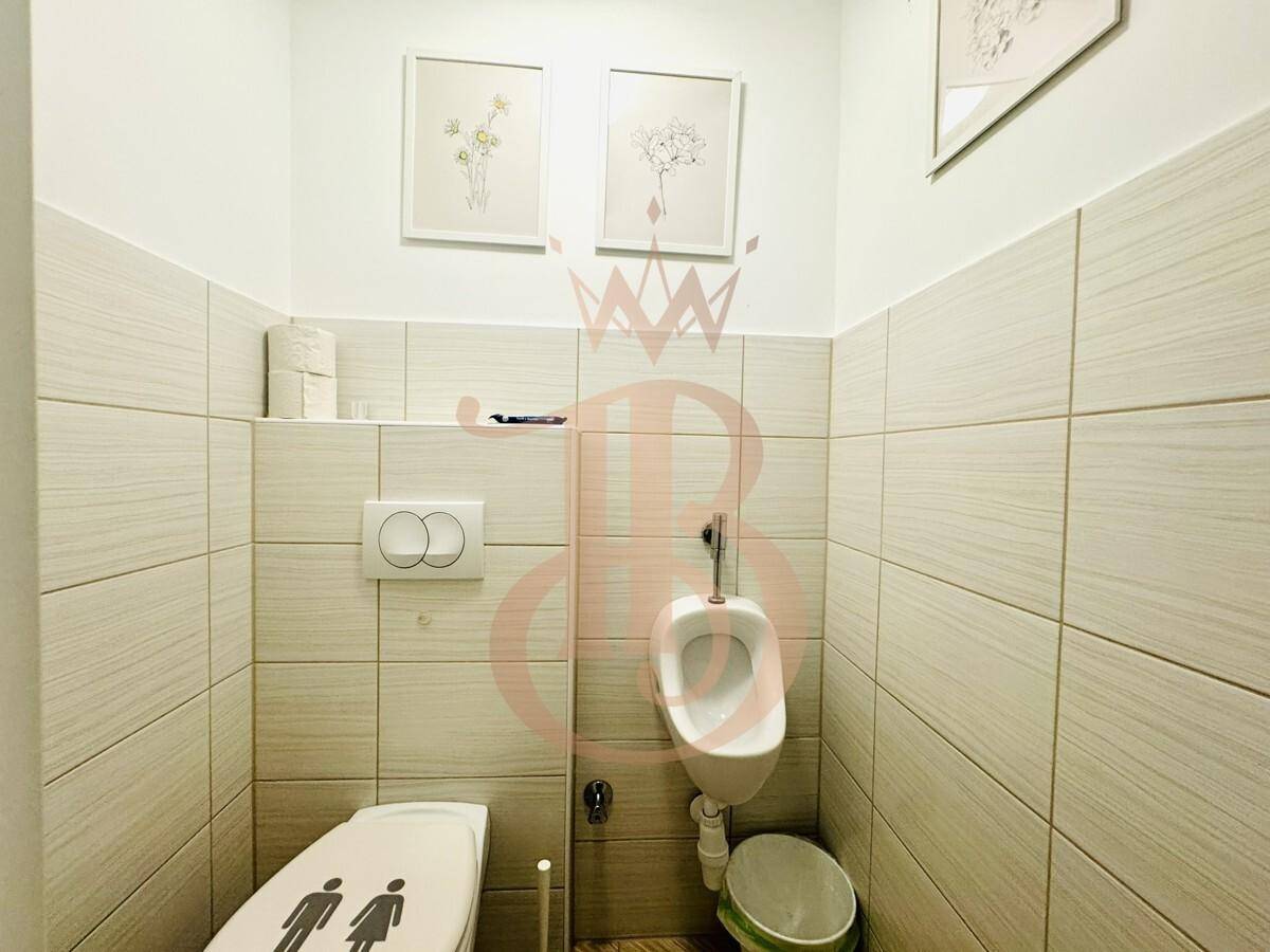 Separate Toilette mit Urinal und modernen Fliesen an den Wänden.