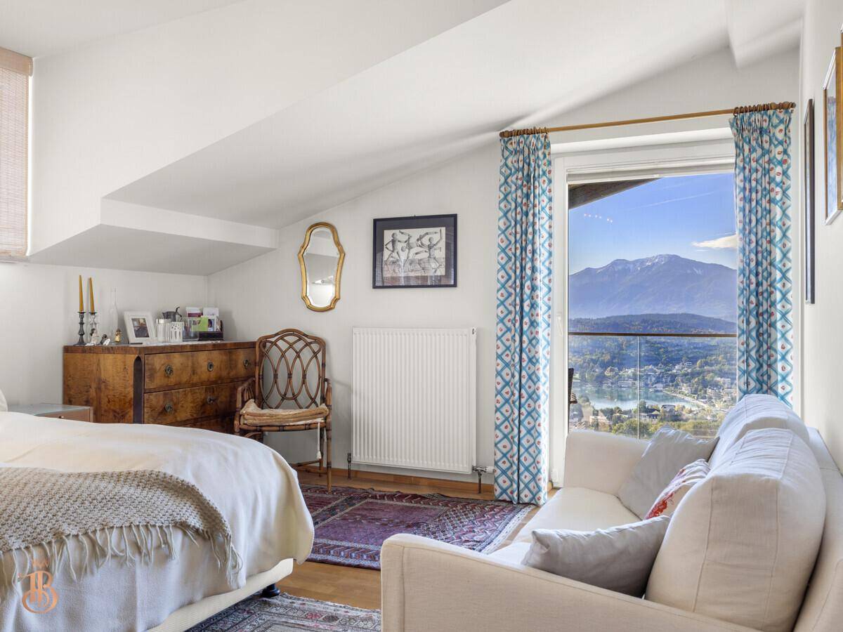 Gemütliches Schlafzimmer mit schrägen Wänden, Holzboden und Fenster mit Bergblick.