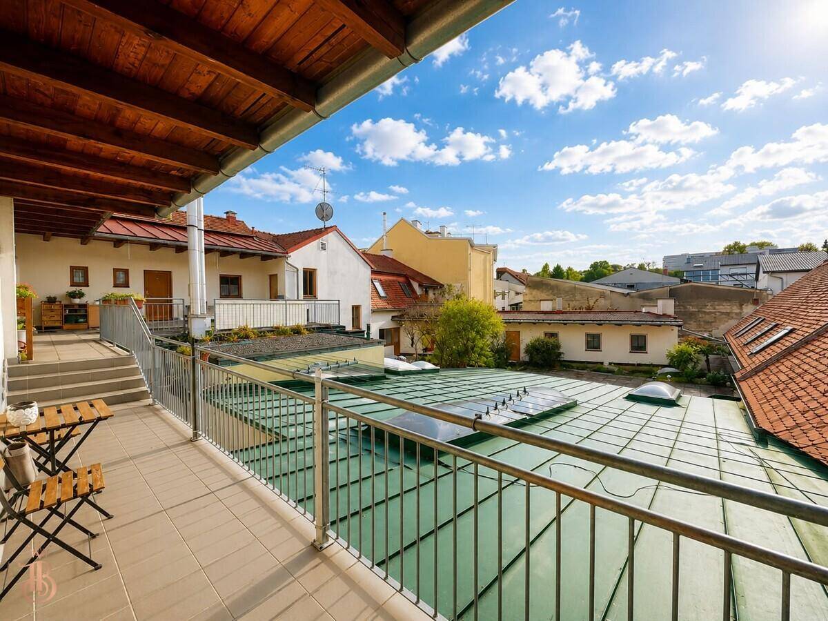 Heller Balkon mit Fliesenboden, Metallgeländer und Blick über die Dächer der Stadt.