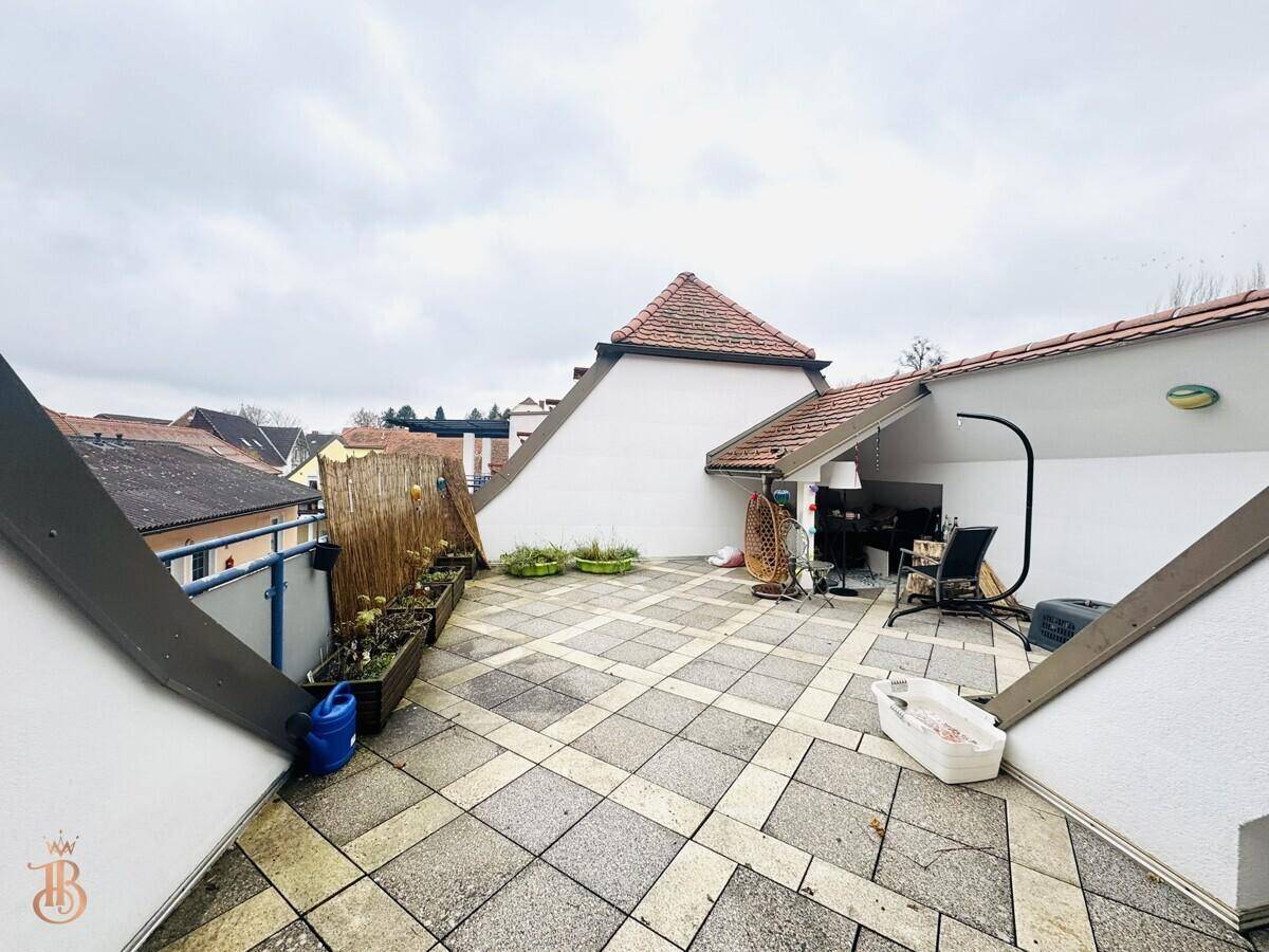 Geräumige Dachterrasse mit Fliesenboden und Blick auf die umliegenden Dächer.