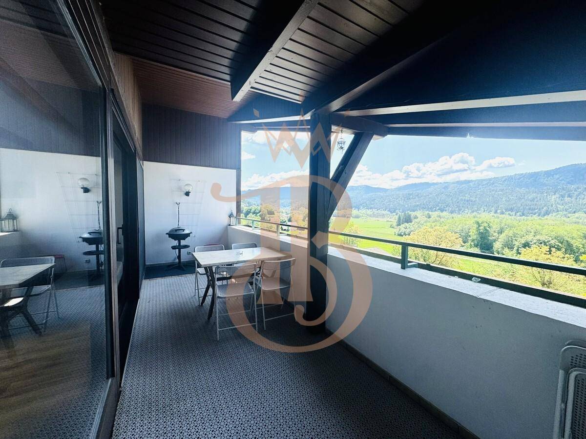 Überdachter Balkon mit Essbereich und Grill, ideal für entspannte Stunden im Freien mit Aussicht.