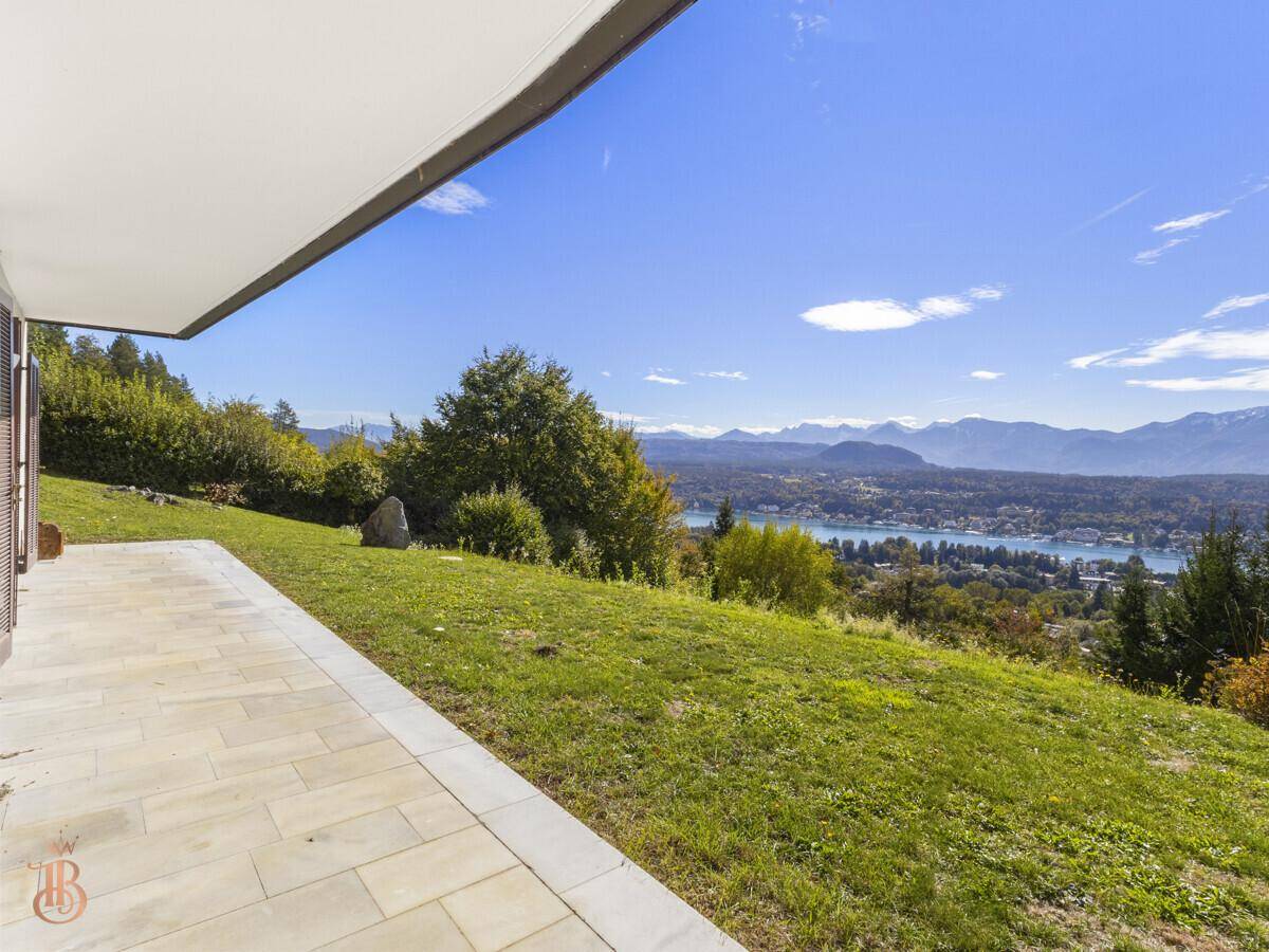 Weitläufige Terrasse mit hellem Fliesenboden und unverbautem Panoramablick auf den See.