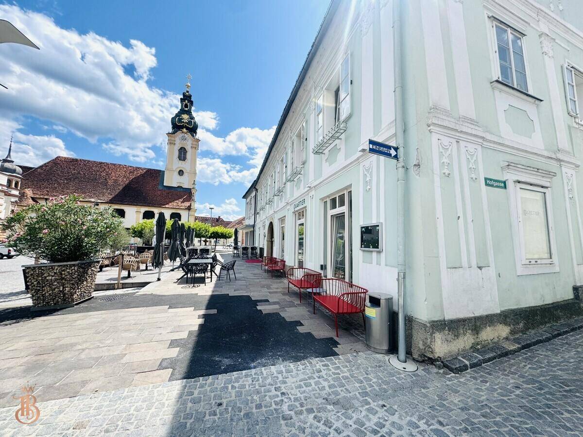 Gebäude an der Straßenecke mit historischer Architektur und einem Kirchturm in der Ferne.