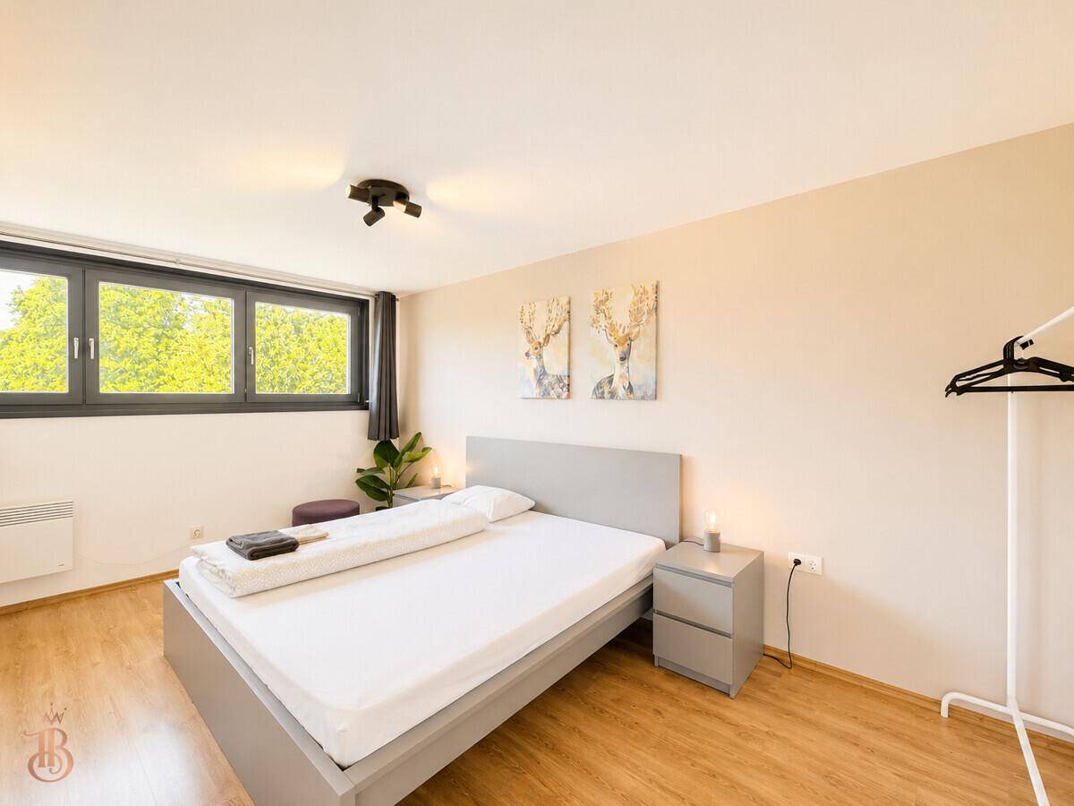 Modernes Schlafzimmer mit Doppelbett, Nachttischen und großem Fenster für viel Tageslicht.