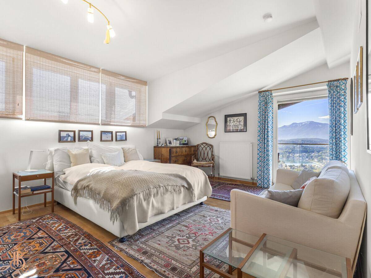 Helles Schlafzimmer mit Holzboden, Teppichen und Zugang zu einem Balkon mit Bergblick.