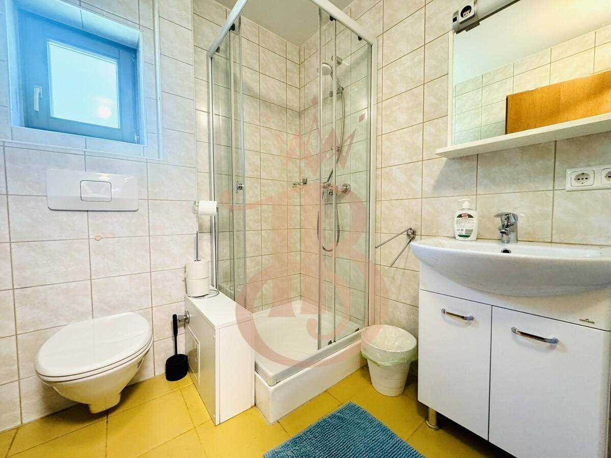 Funktionales Badezimmer mit Duschkabine, WC und Fenster für Tageslicht.
