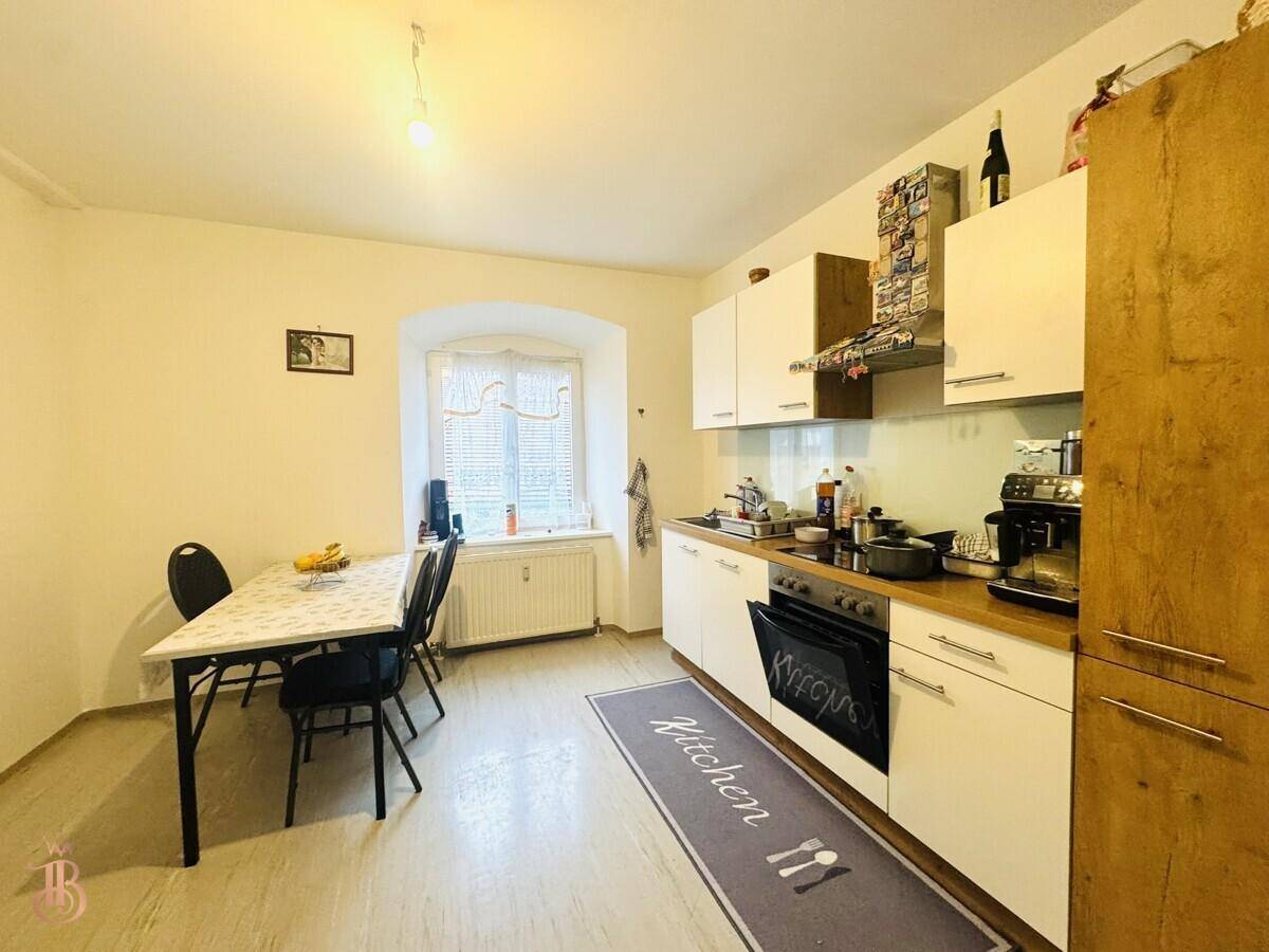 Funktionale Küche mit weißen Schränken, Esstisch und Fenster für natürliches Licht.