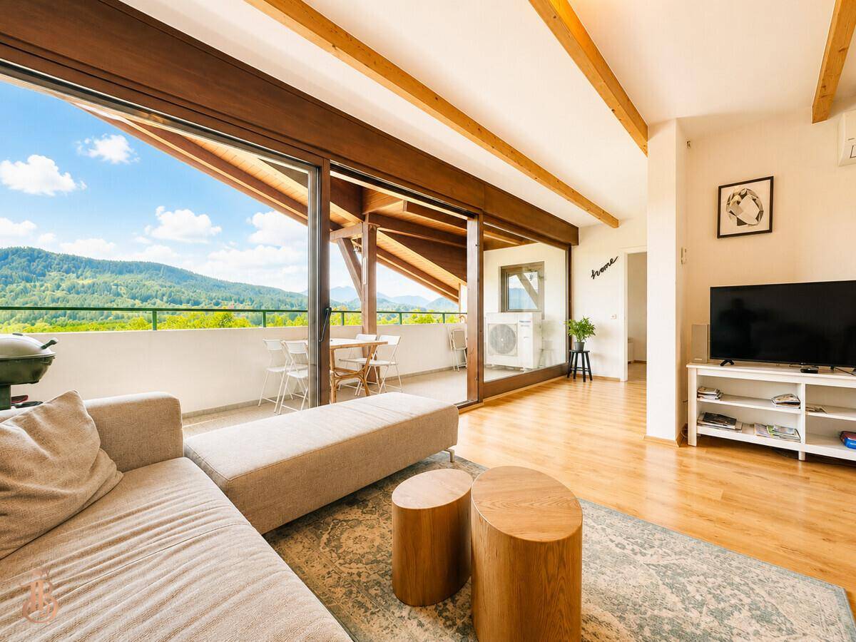 Lichtdurchflutetes Wohnzimmer mit bequemer Couch und weitem Blick auf die umliegende Berglandschaft.