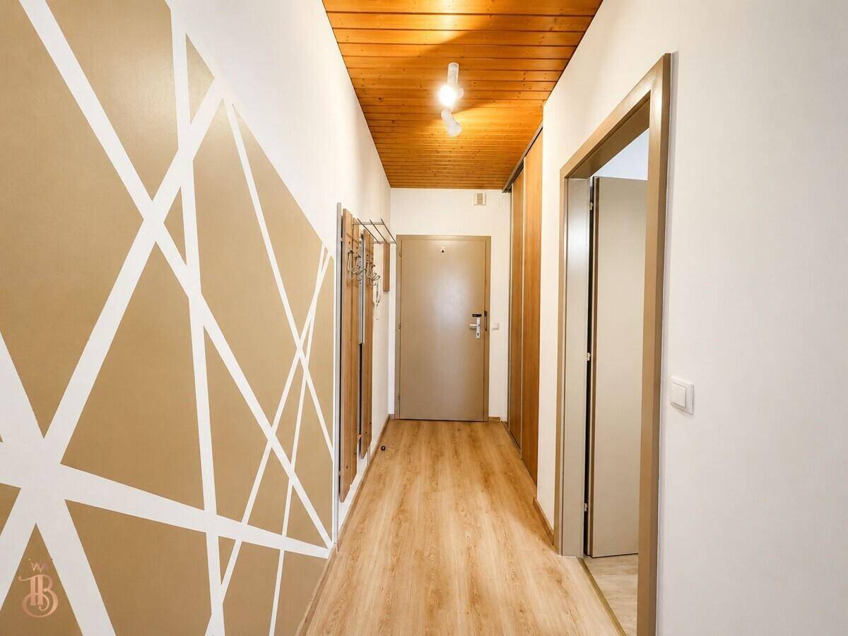 Heller Flur mit dekorativer Wandgestaltung, Holzbalkendecke und Laminatboden.