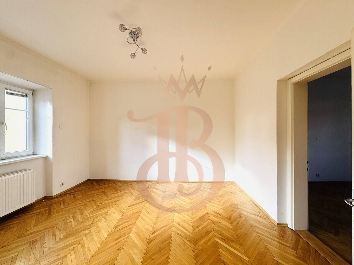 Geräumiges Zimmer mit Fischgrätparkettboden und einem Fenster, das viel Tageslicht hereinlässt.