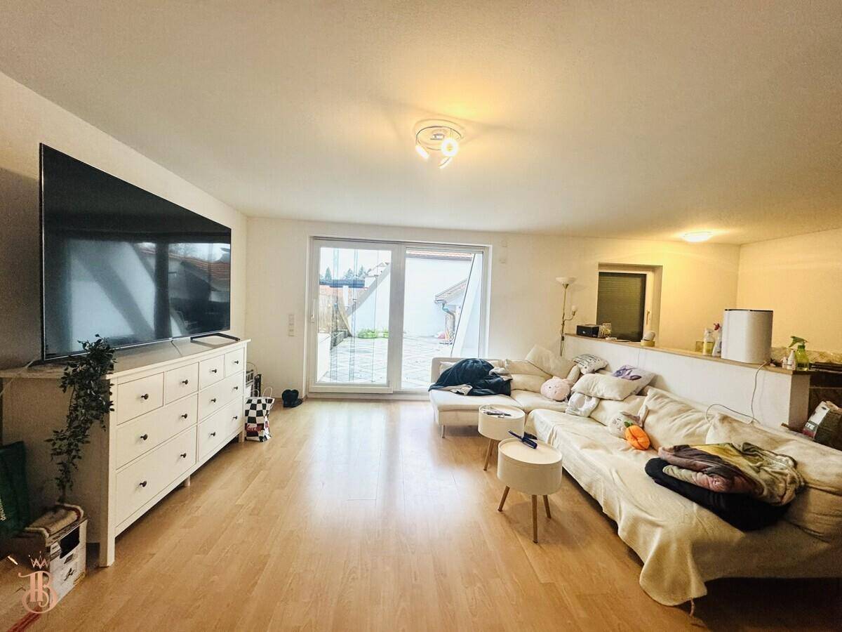 Gemütliches Wohnzimmer mit hellem Holzboden, großem Sofa und Zugang zur Terrasse.
