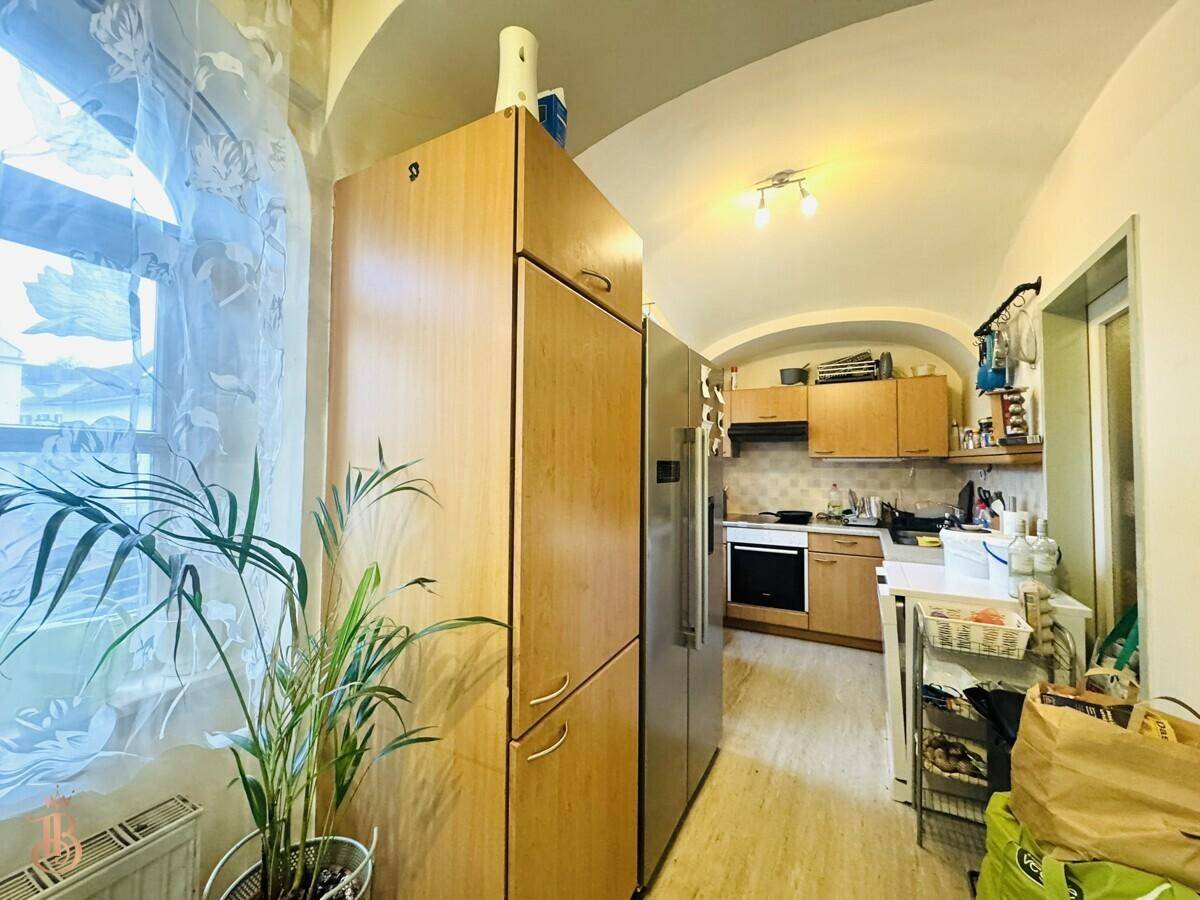 Küchenbereich mit großem Kühlschrank, Holzschränken und einer Gewölbedecke, praktisch und geräumig.