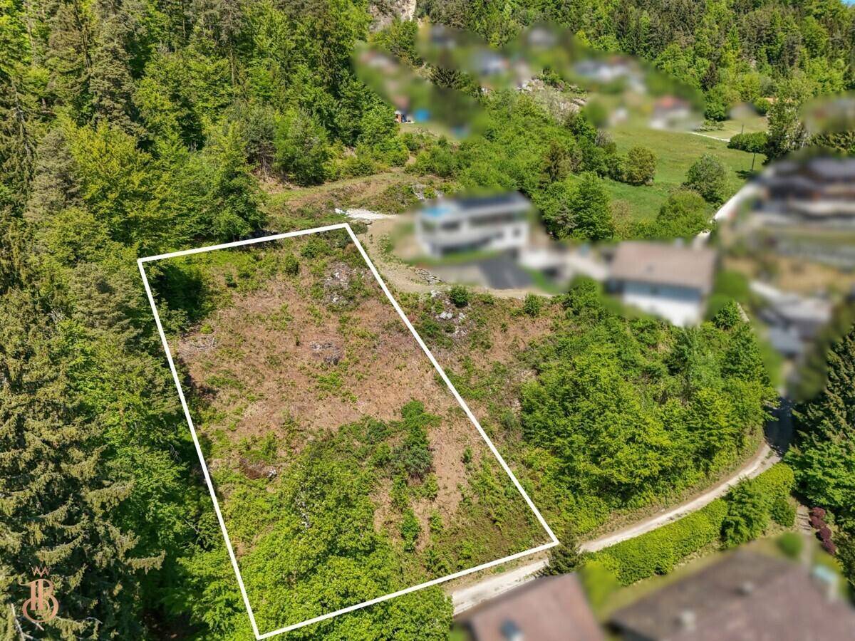 Luftaufnahme eines Baugrundstücks, umgeben von Wald und mit Potenzial für Neubauprojekte.