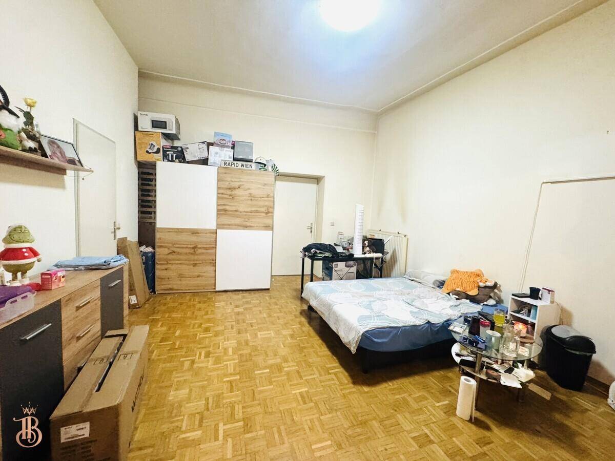 Geräumiges Schlafzimmer mit Holzboden, Bett und einem großen Kleiderschrank, einfach eingerichtet.