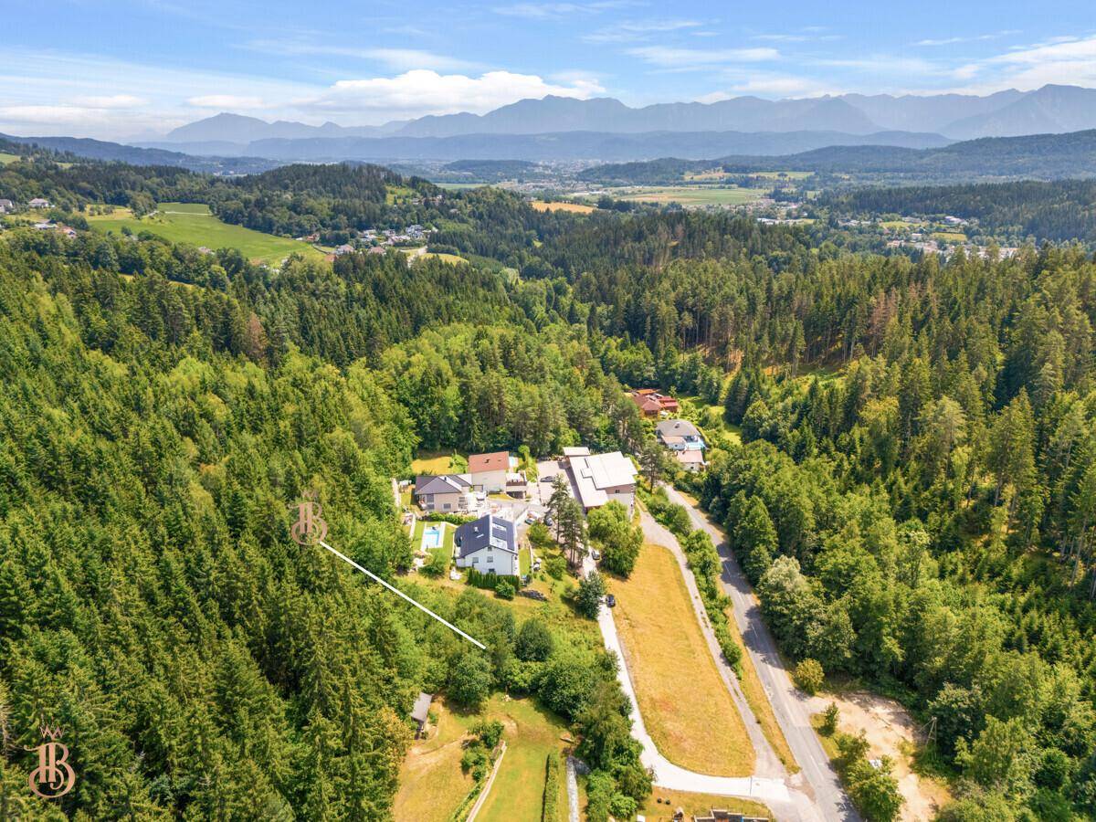 Panoramablick auf das Grundstück, eingebettet in eine grüne Landschaft mit Bergen am Horizont.