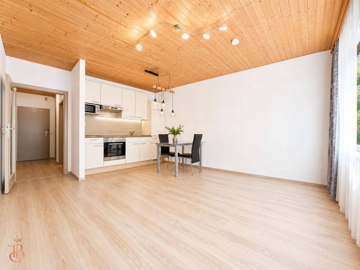 Wohnküche mit Essbereich, Holzbalkendecke und Zugang zum Flur, ausgestattet mit modernen Möbeln.