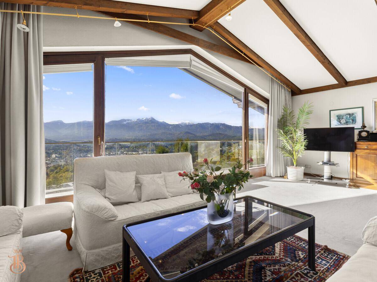 Gemütliches Wohnzimmer mit bequemen Sofas, Holzbalken und weitem Blick auf die Berglandschaft.