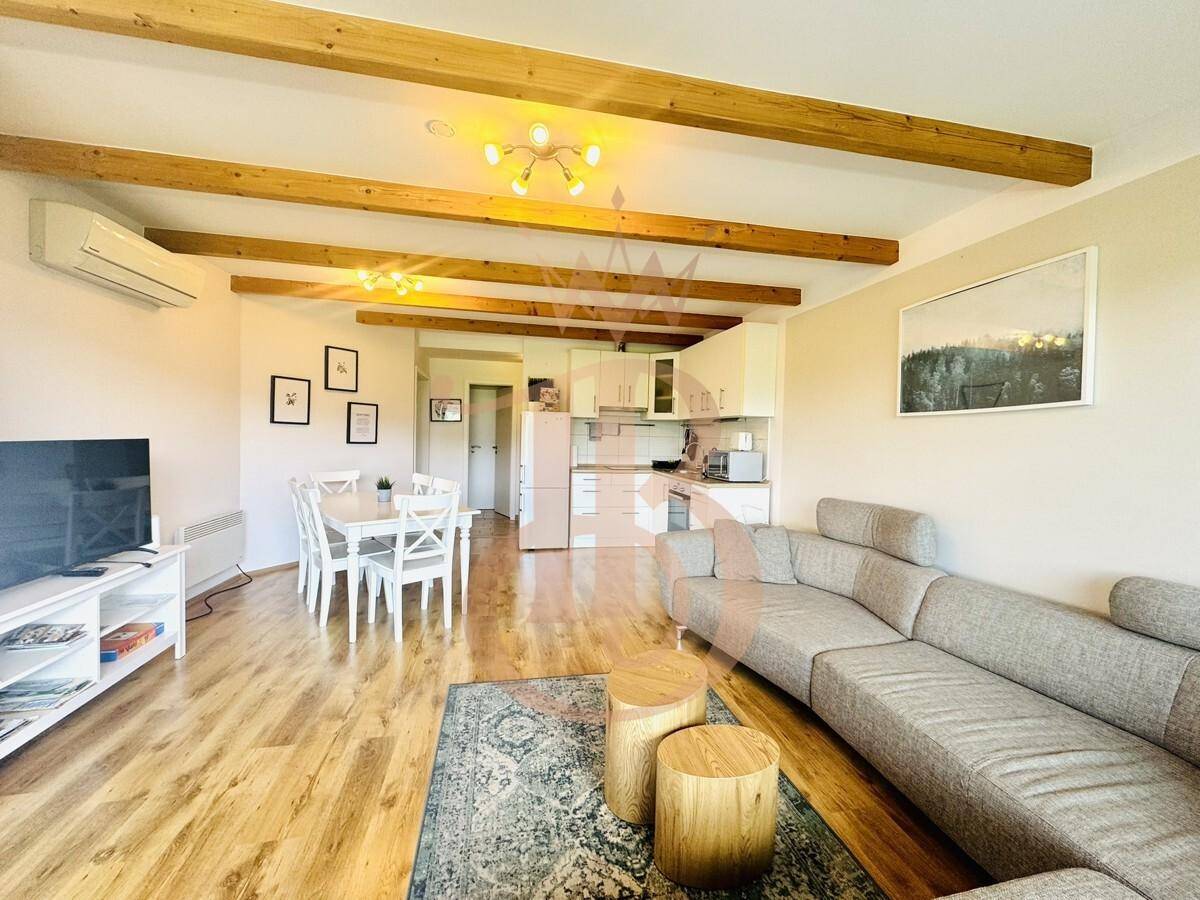 Heller Wohn- und Essbereich mit offener Küche, Holzbalken und modernem Interieur.