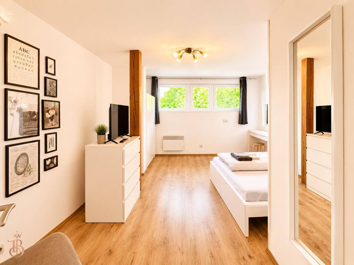 Geräumiges Schlafzimmer mit Doppelbett, Kommode und dekorativen Bildern an der Wand.