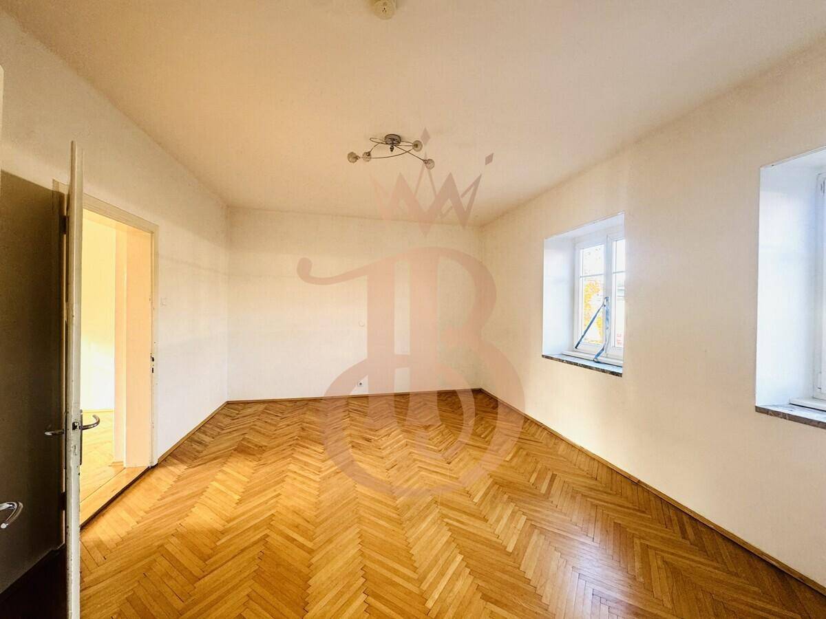 Helles Zimmer mit Fischgrätparkettboden und Fenster, das viel Tageslicht hereinlässt.