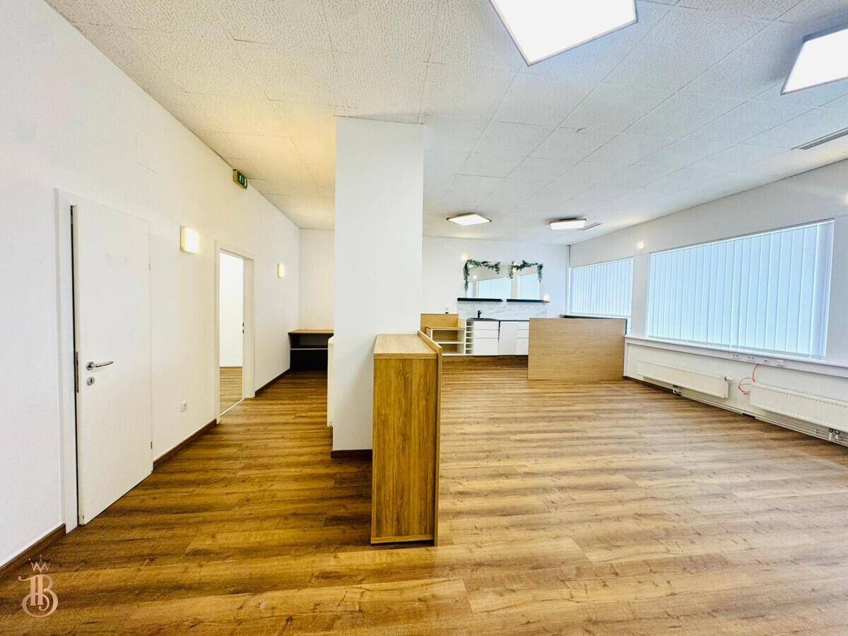 Heller, offener Wohnbereich mit Laminatboden und Zugang zu weiteren Räumen.