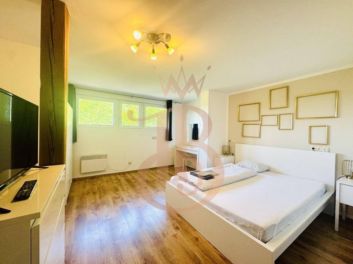 Modern eingerichtetes Schlafzimmer mit Holzboden, großem Bett und dekorativen Rahmen an der Wand.