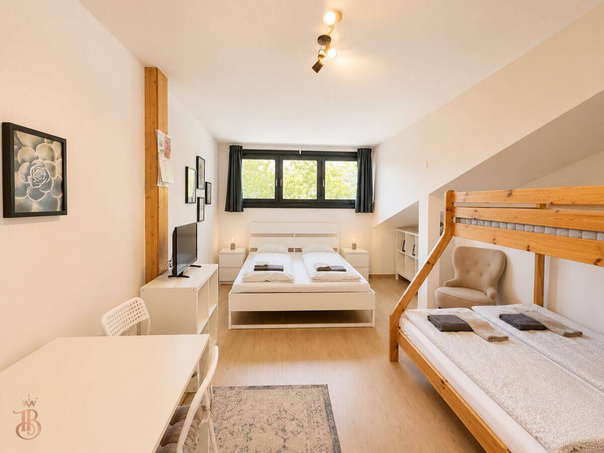 Geräumiges Schlafzimmer mit Doppelbett, Etagenbett, Esstisch und Fernseher, ideal für Familien.