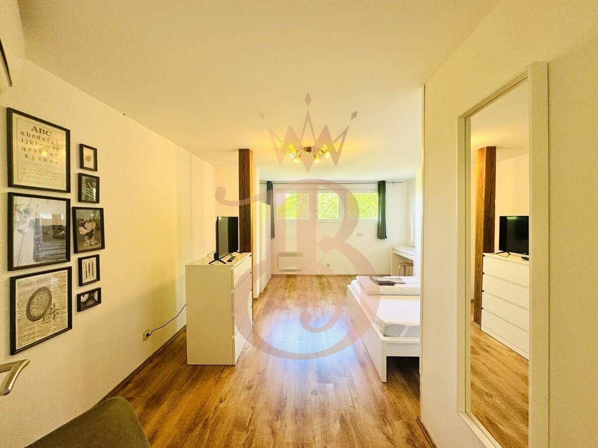 Helles Schlafzimmer mit Holzboden, modernem Bett und Zugang zu einem weiteren Bereich.