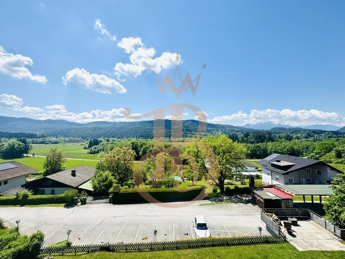 Außenansicht mit Parkplätzen und einem weiten Blick über die grüne Landschaft und Berge.