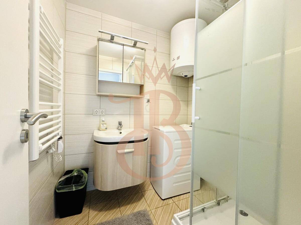 Modernes Badezimmer mit Duschkabine, Waschbecken und beheiztem Handtuchhalter.