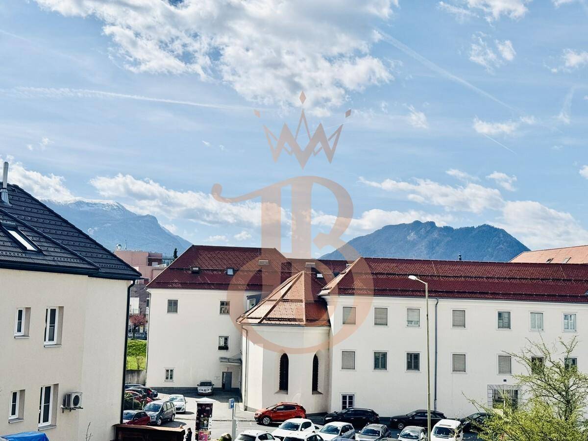 Panoramablick auf die umliegende Berglandschaft und benachbarte Gebäude unter blauem Himmel.
